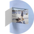 Person zieht Freund auf Schlitten durch verschneite Winterlandschaft