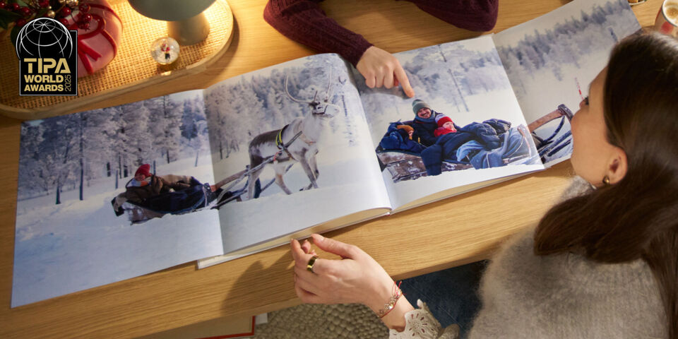 Eine Mutter und ihr Kind betrachten Familienfoto auf einer Panoramaseite in einem CEWE FOTOBUCH.